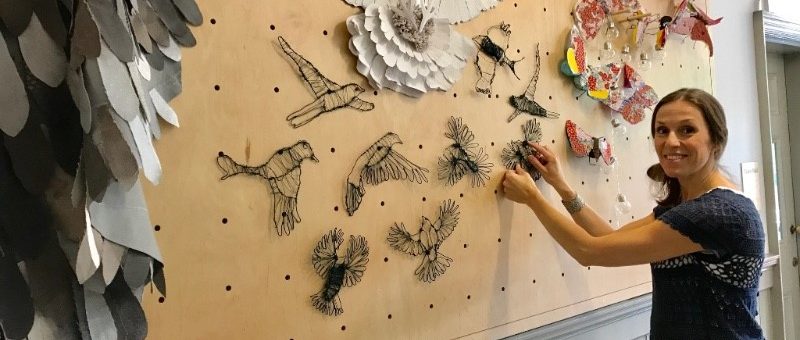 Photo of woman putting up sculptures on the Frome Town Hall exhibition board.