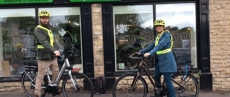 Photo of two people on EBikes outside Cycology bike shop.