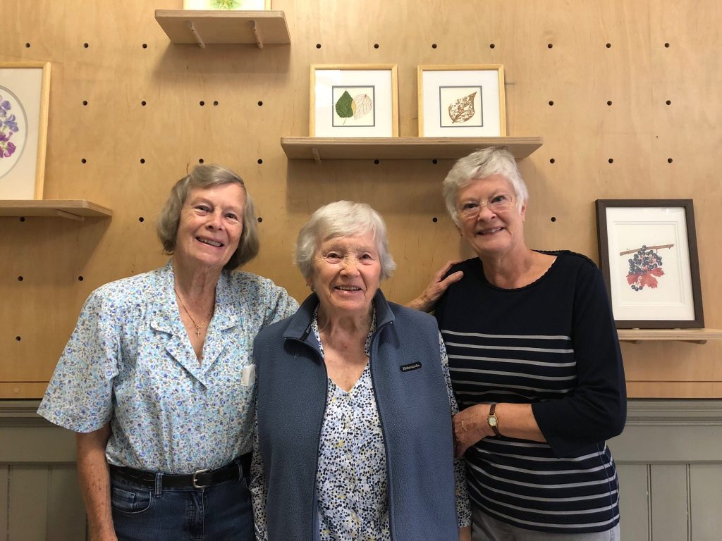 Photo of the 'Late Bloomers' artists, Hazel, Margaret and Shirley in front of their artwork.