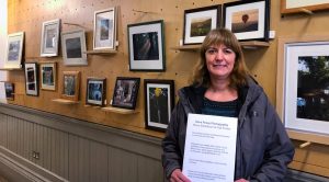 Lenka Grimes of Fair Frome standing in front of Dave Povey exhibition