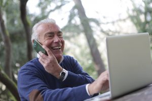 Elderly Gentleman chatting on phone in front of laptop