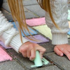 Child drawing with chalk on pavement