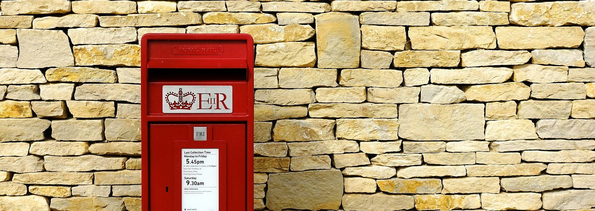 Red post box against brick wall