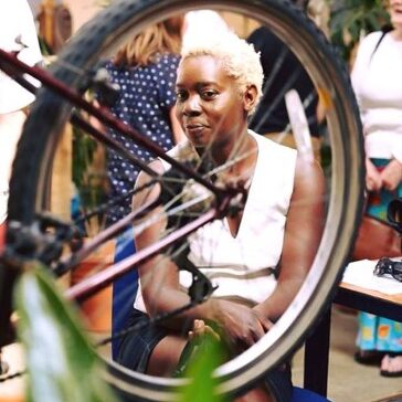 Picture of a woman looking through the spokes of a wheel at the transition shed