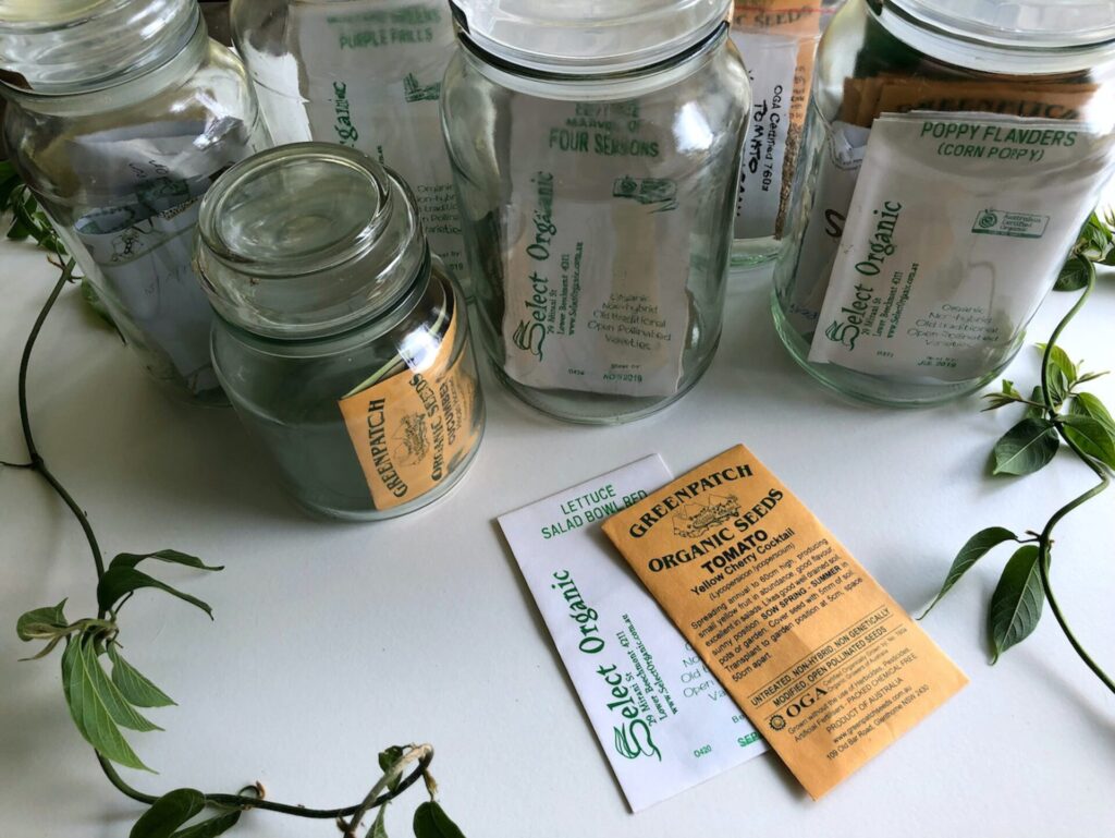 A variety of seeds in packets and glass jars