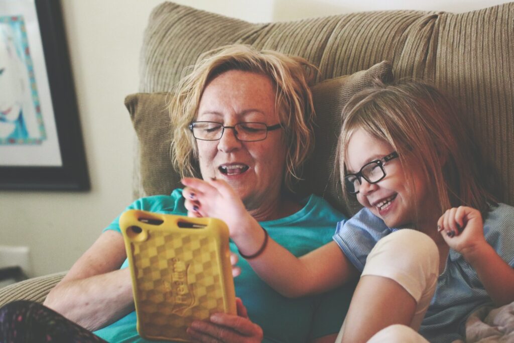 Woman and child sit on chair together and look at tablet