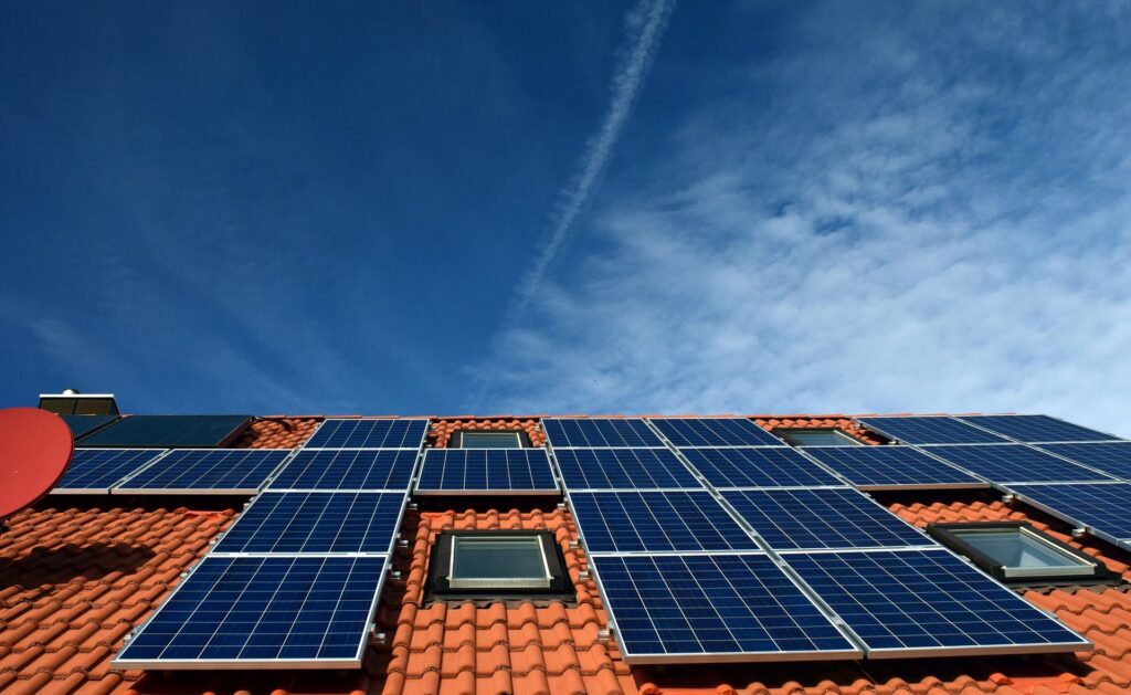 Solar panels fixed to a roof, with a blue sky above