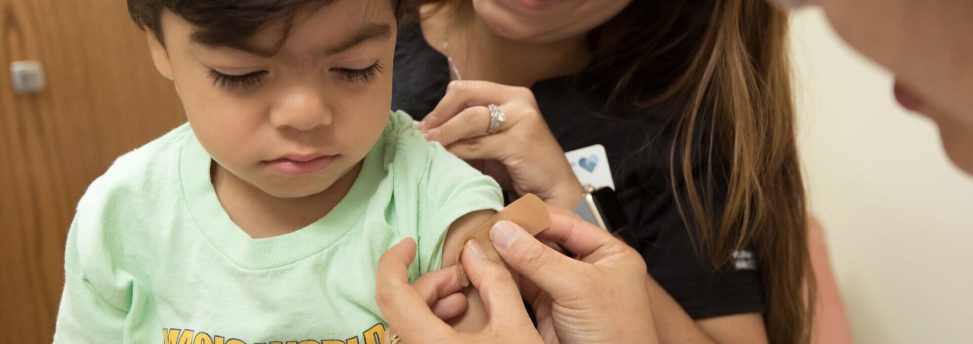 nurse putting plaster on child's arm