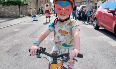 A young boy with a red mask sits on a yellow bike