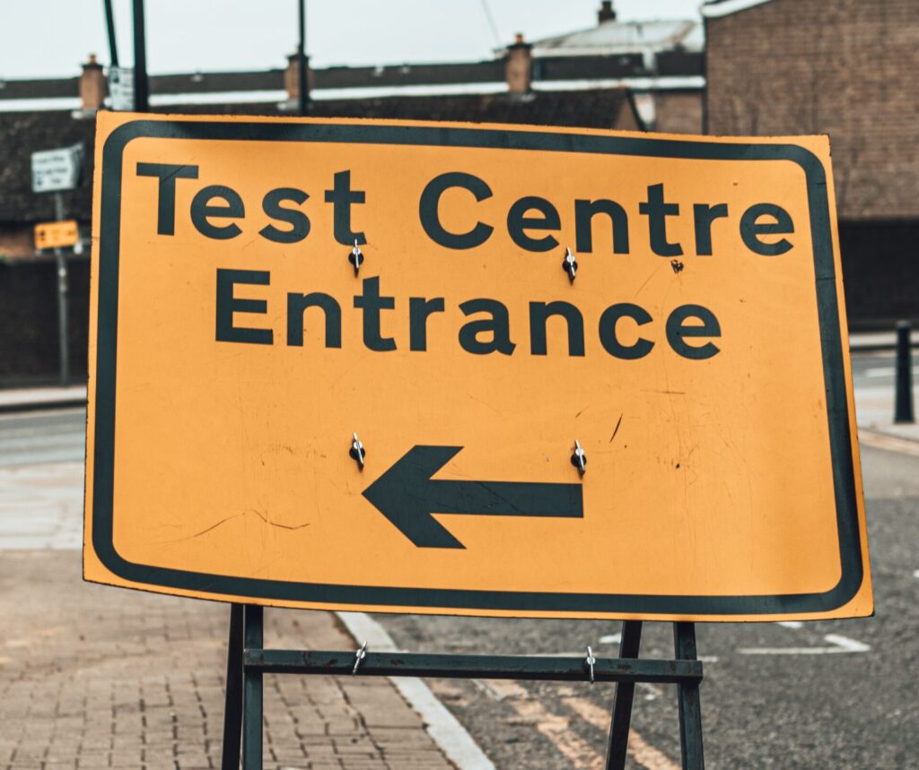 Yellow road sign reading Test Centre Entrance