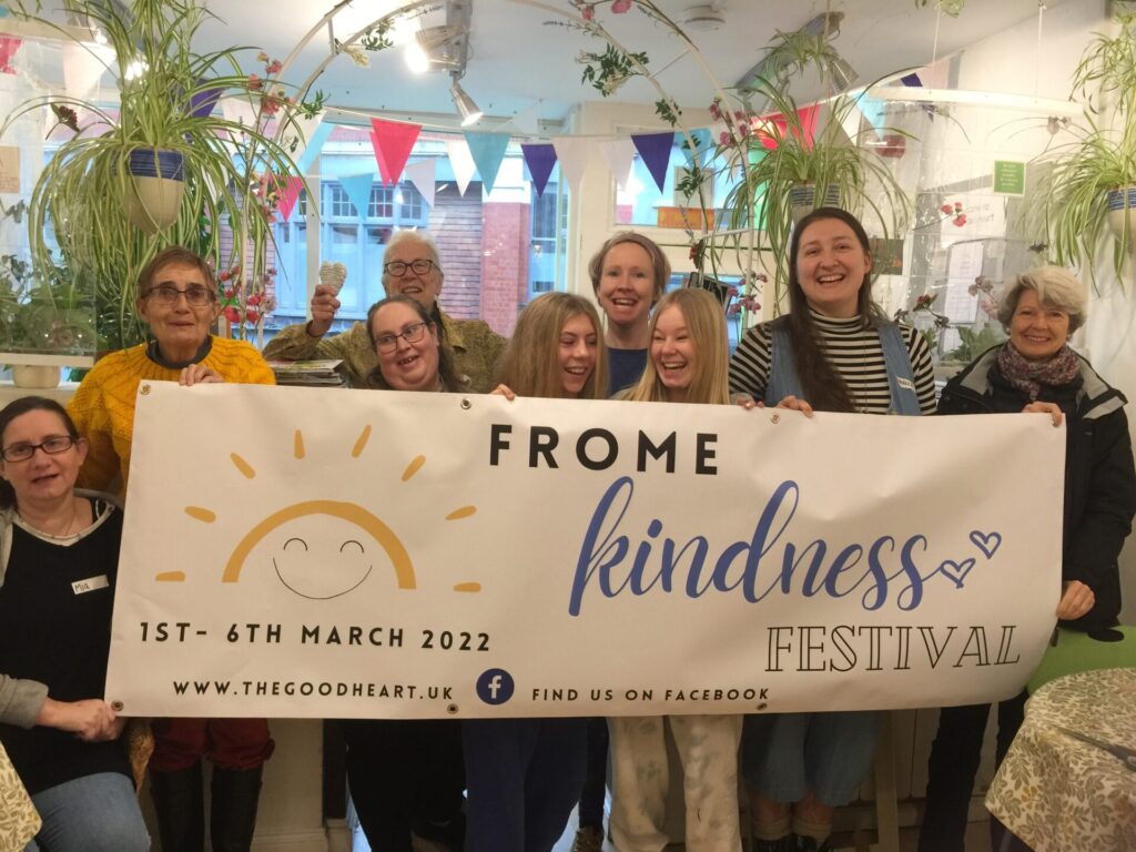 A group of people hold the Frome Kindness Festival Banner