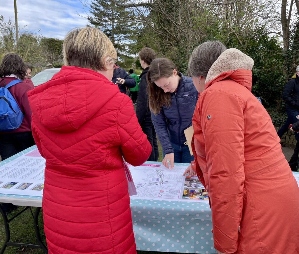 Group of people discussing plans whilst leaning over and pointing at a map displaying the proposals for School Streets. 