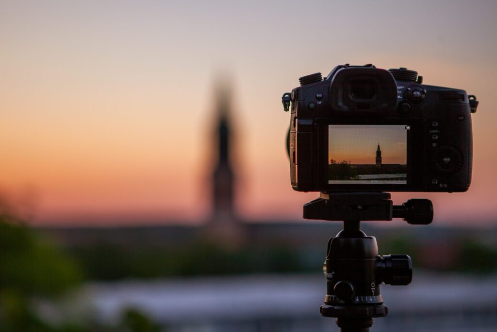 Camera on tripod filming a pink-orange sunset. 
