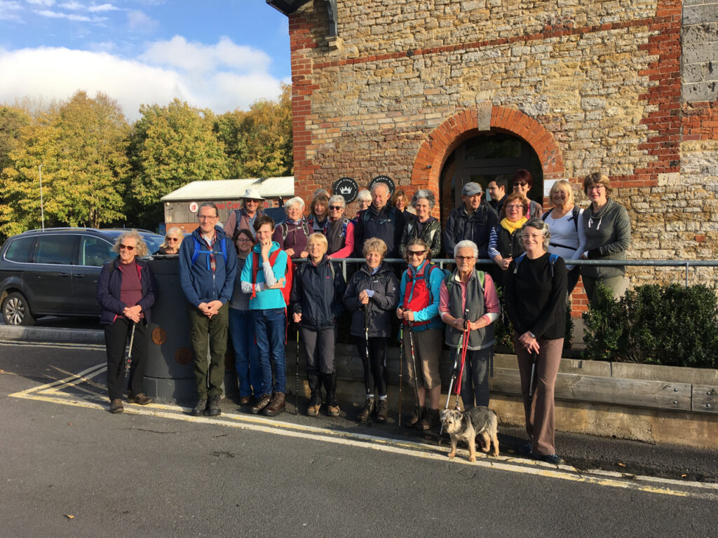 A group of people standing in front of the Cheese & Grain dressed in walking gear.