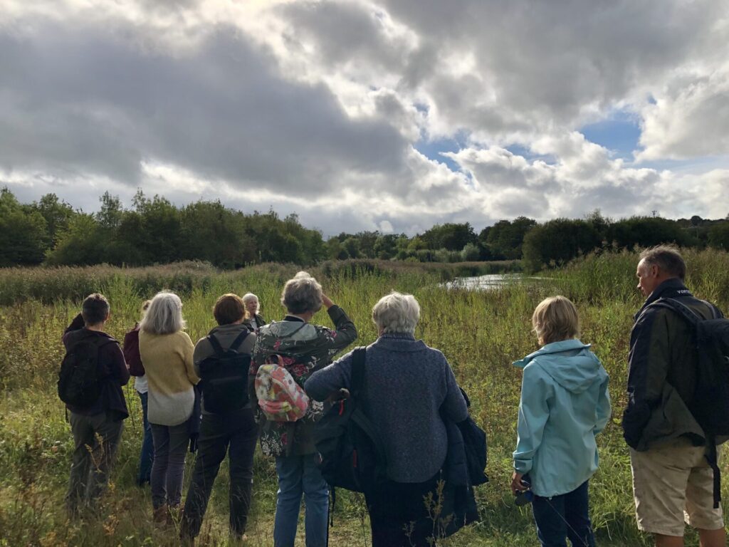 A group of people in walking gear overlooking a nature reserve