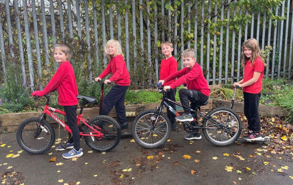 A group of children on bikes, scooters and walking