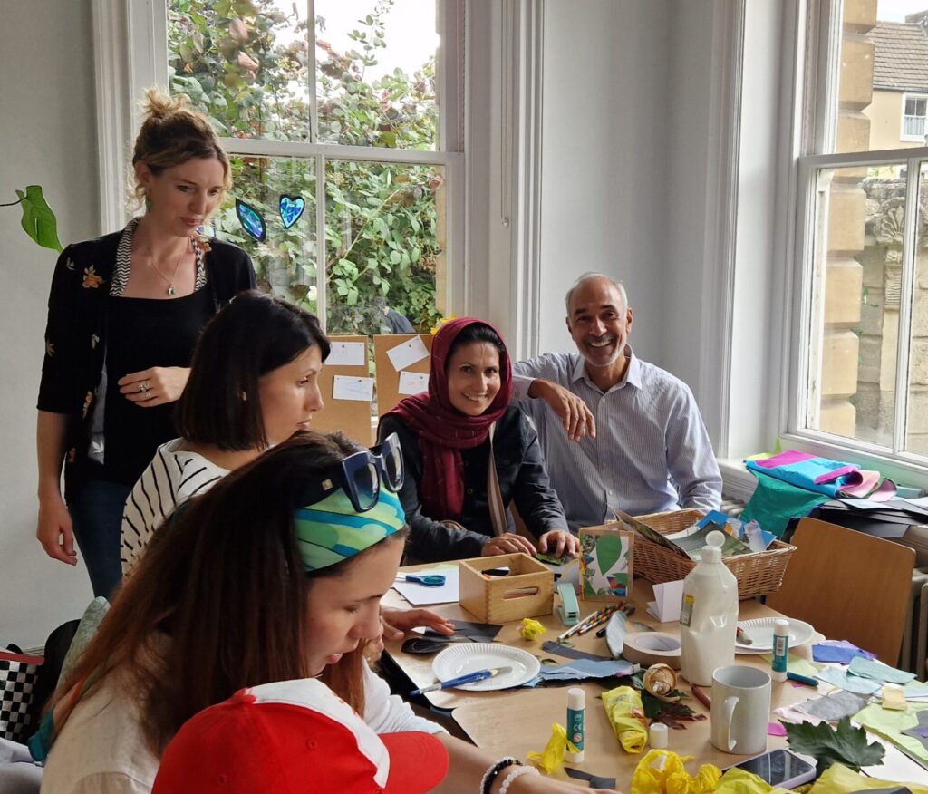 Families doing arts and crafts at Frome Welcome Hub with one family smiling to the camera 